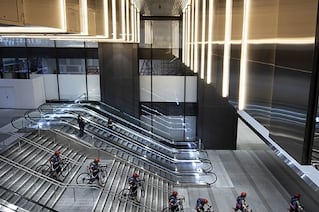 People with bikes going down sets of stairs inside a building