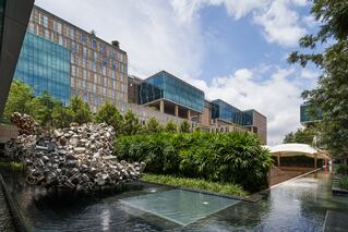 a large building with some water in front and greenery