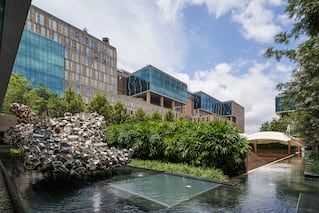 a large building with some water in front and greenery