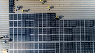 Crew installing solar panels on roof of building