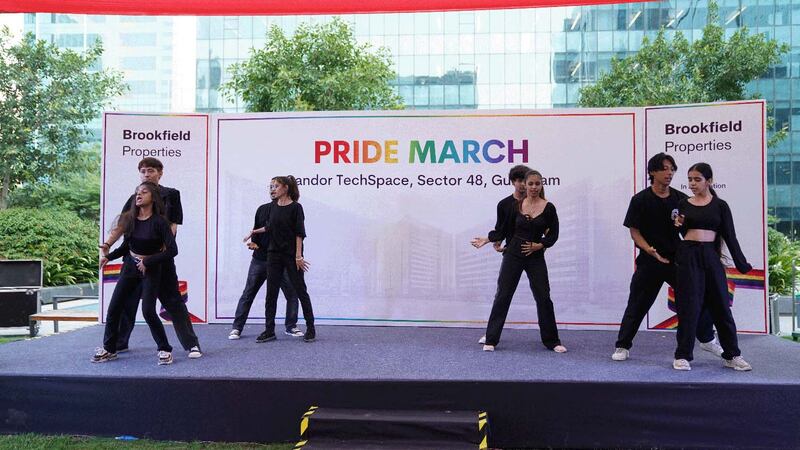 dancers in black in front of Pride March sign on stage