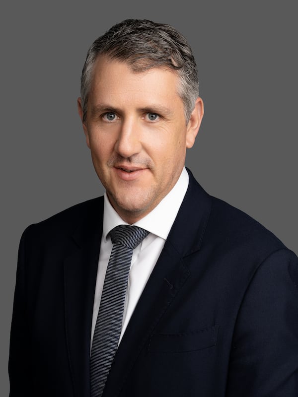 A male headshot dressed in a business suit, shirt and tie