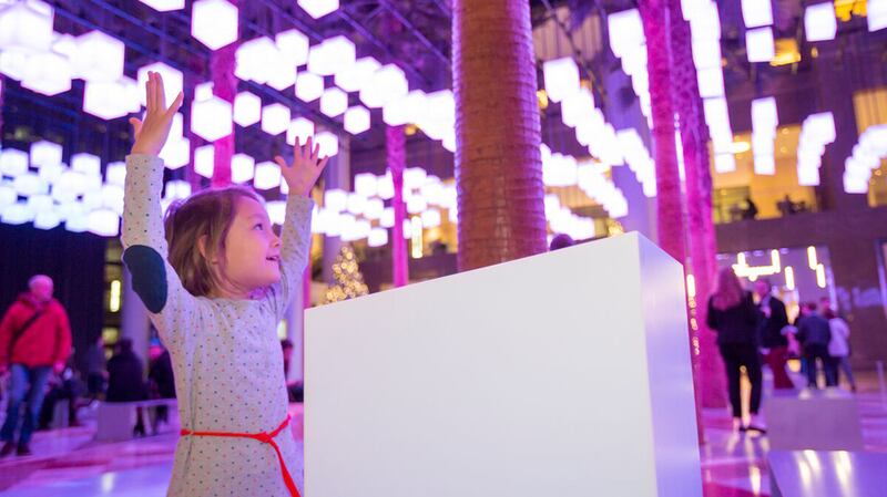 girl holding up hands under lights