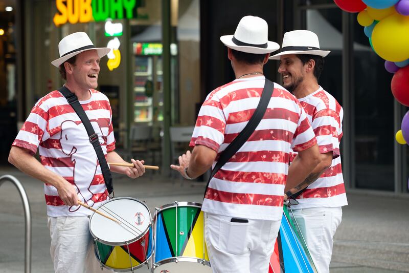 three individuals performing with Brazilian drums