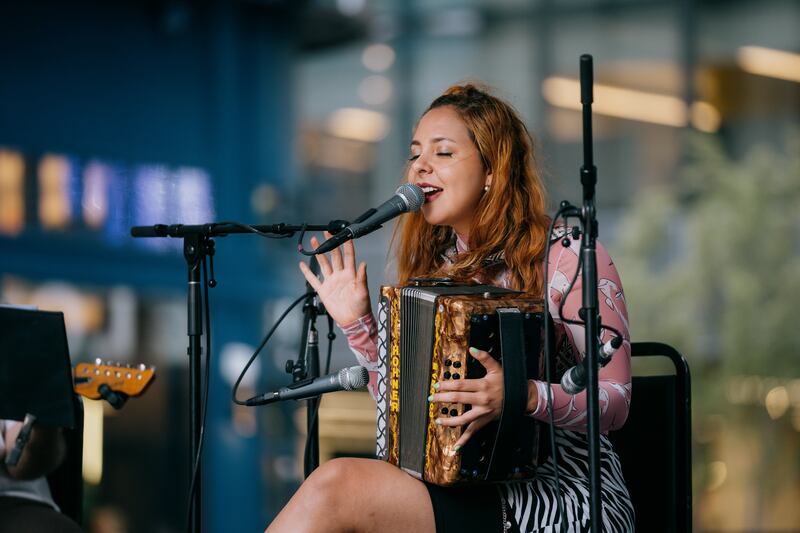 A woman singing into a microphone and holding a accordian