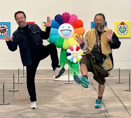Two male artists posing in front of a colorful flower sculpture