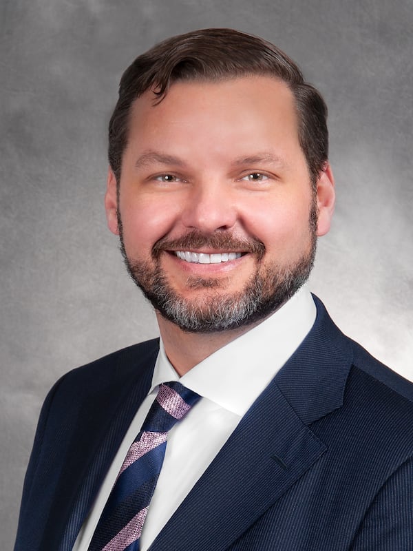 A photo of a man wearing a dark suit with a tie