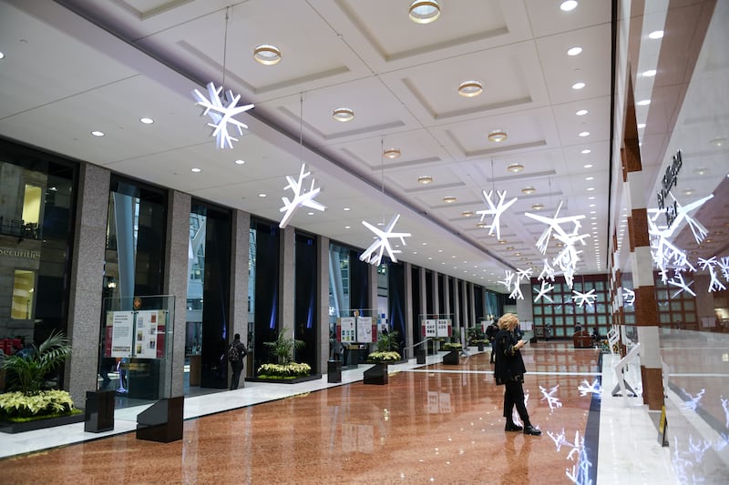 LED sculptural snowflakes are hung in a lobby with white and brown stripes walls, marble floor and glass windows along one side.