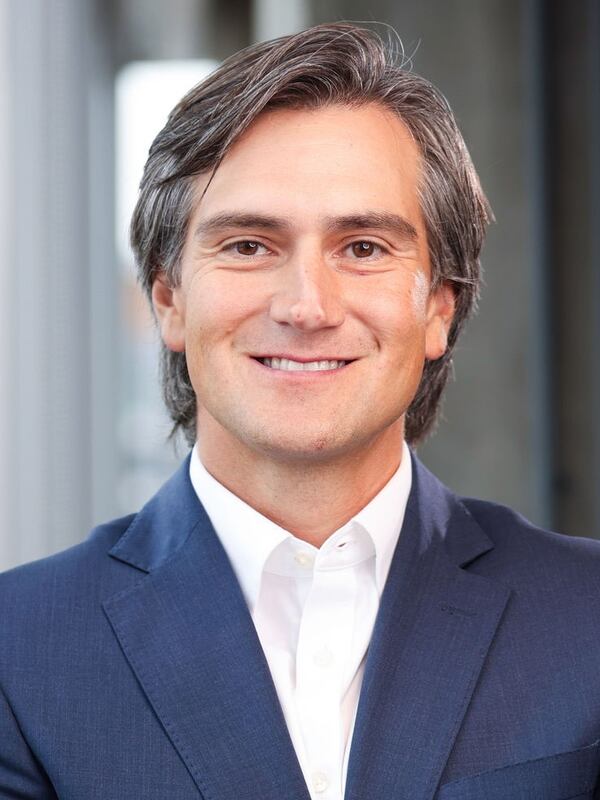 Headshot of man wearning white collared shirt and blue blazer