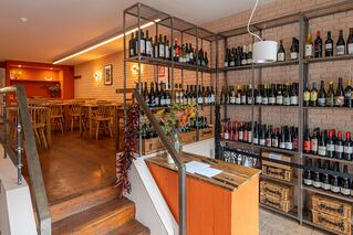A rack with wine on it and some steps on the left with some tables in the area at the top of the steps