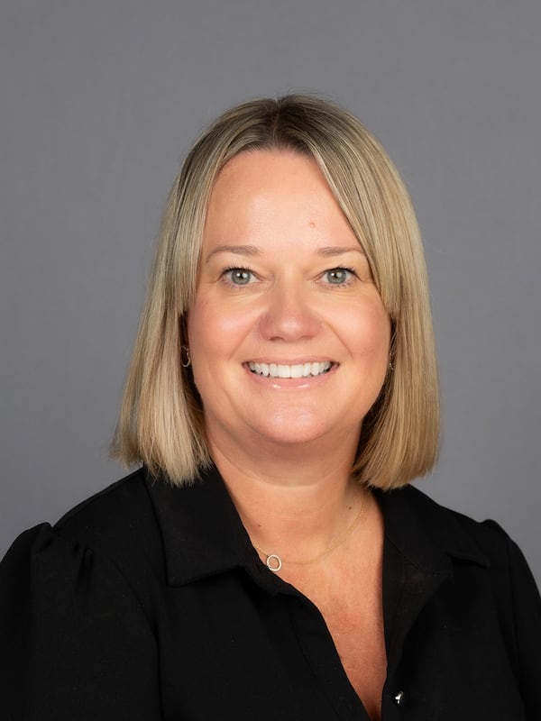 headshot of a white woman with mid length blond hair and a black button down shirt.