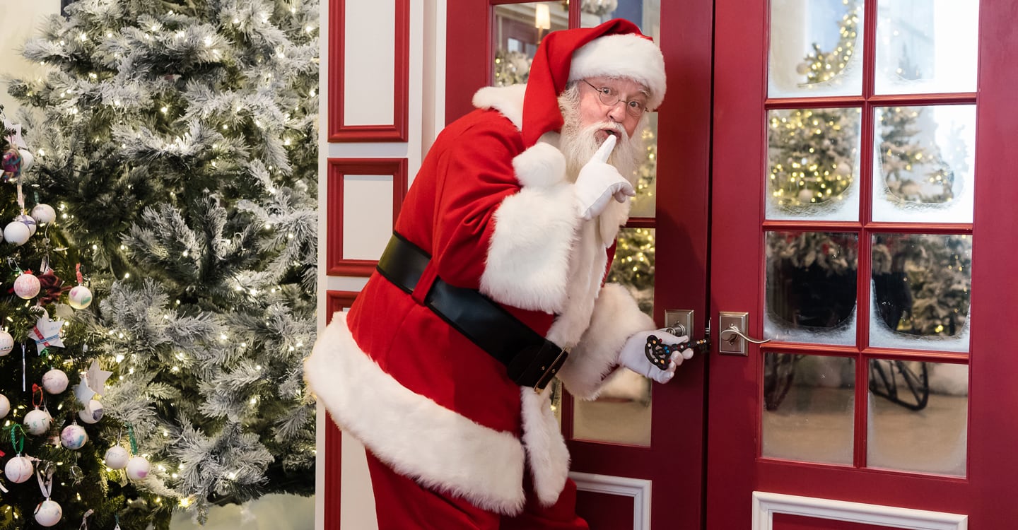 Santa at door making "quiet" gesture