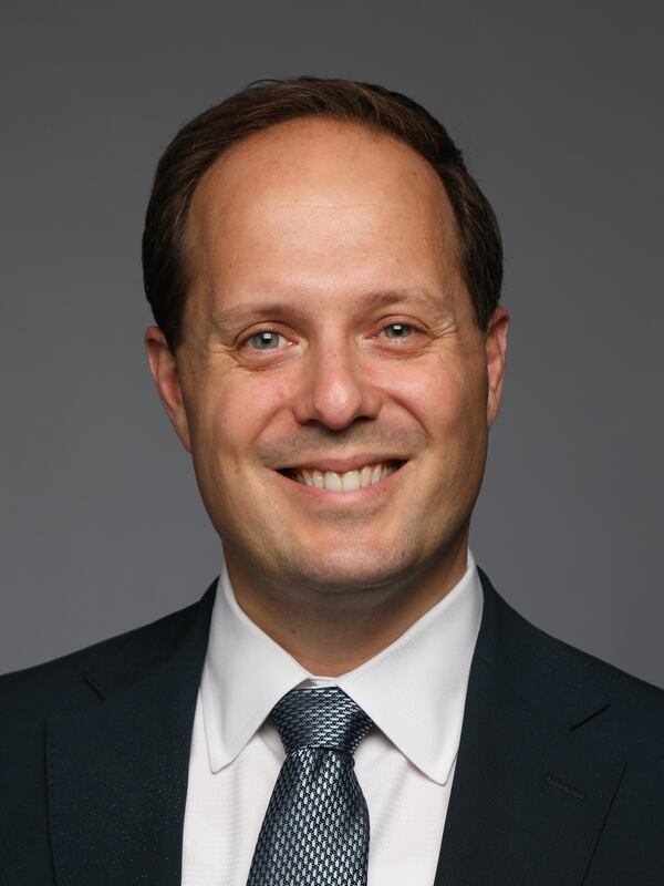 headshot of a man in suit with white shirt and blue tie