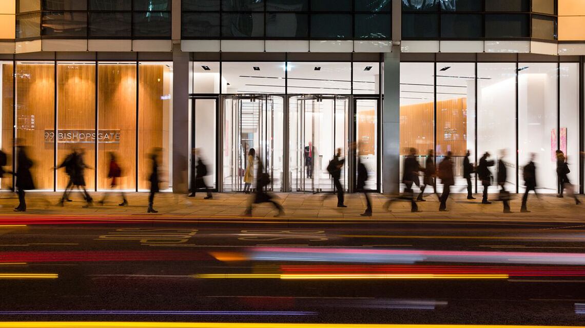 blurred image of people walking in front of office building at night