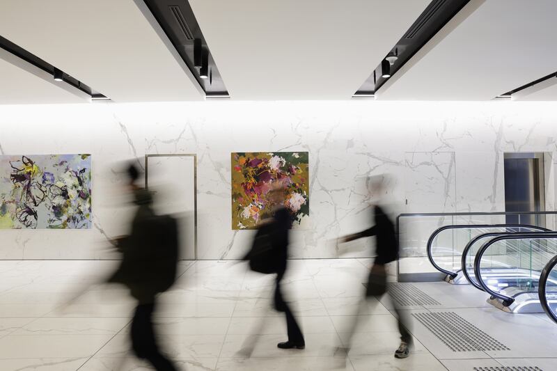 Abstract floral painting on a marble wall with people walking past.