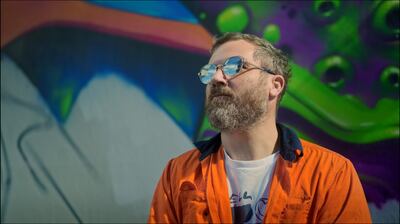 Artist Russell Fenn, better known as Sofles, in front of the mural
