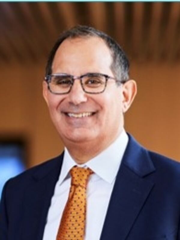 White man wearing a suit with a yellow tie and blue blazer, also wearing glasses