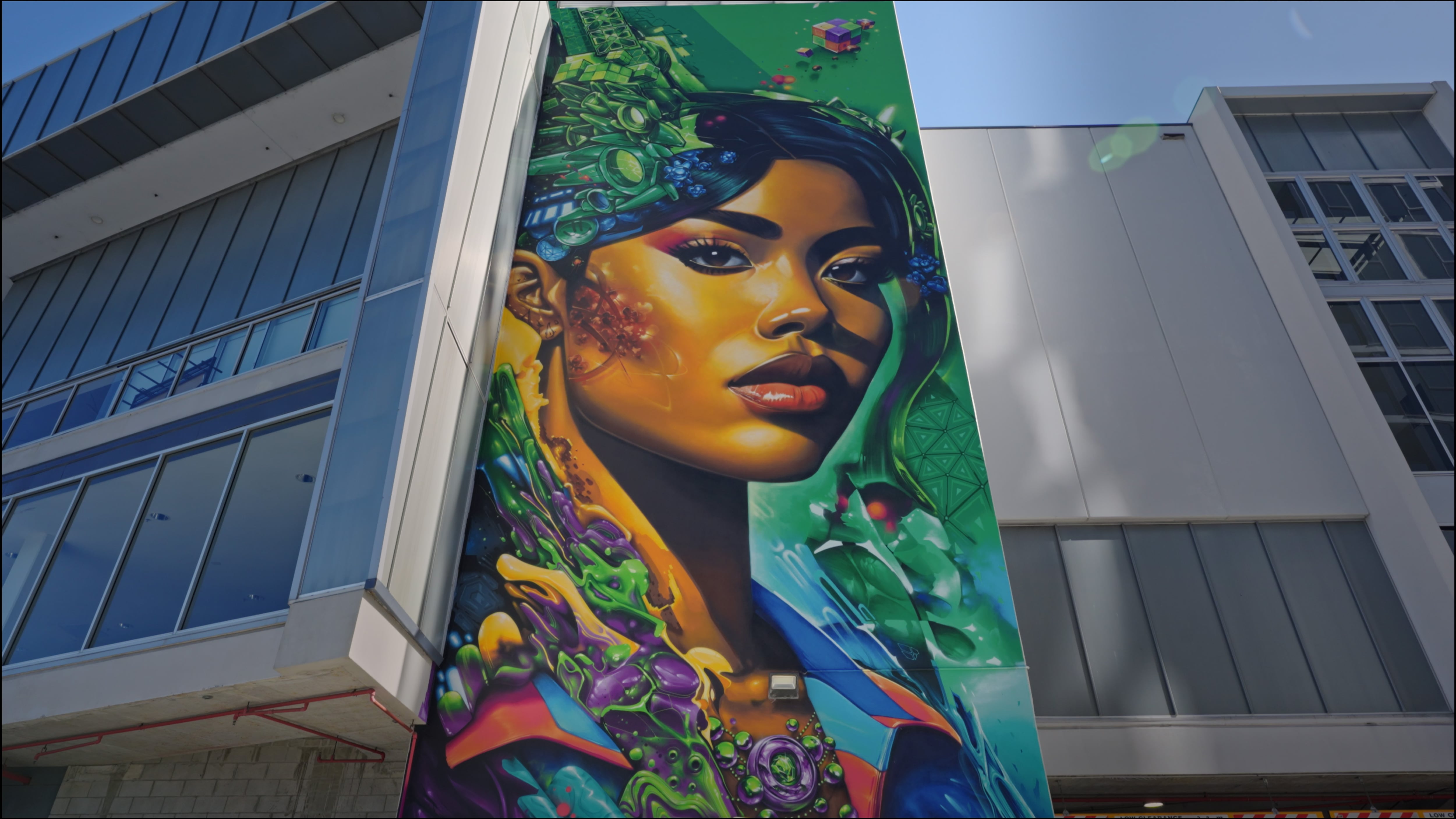 "Portside Portal" mural of a woman with dark features surrounded by colorful shapes and designs