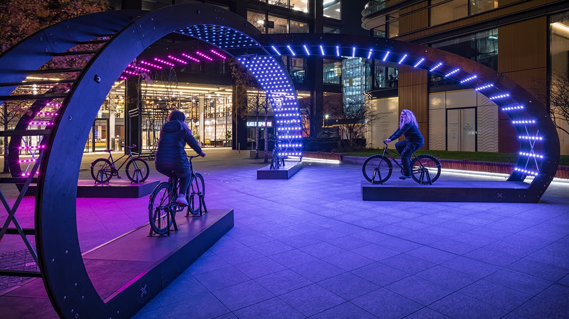 people on bike sculptures under lights