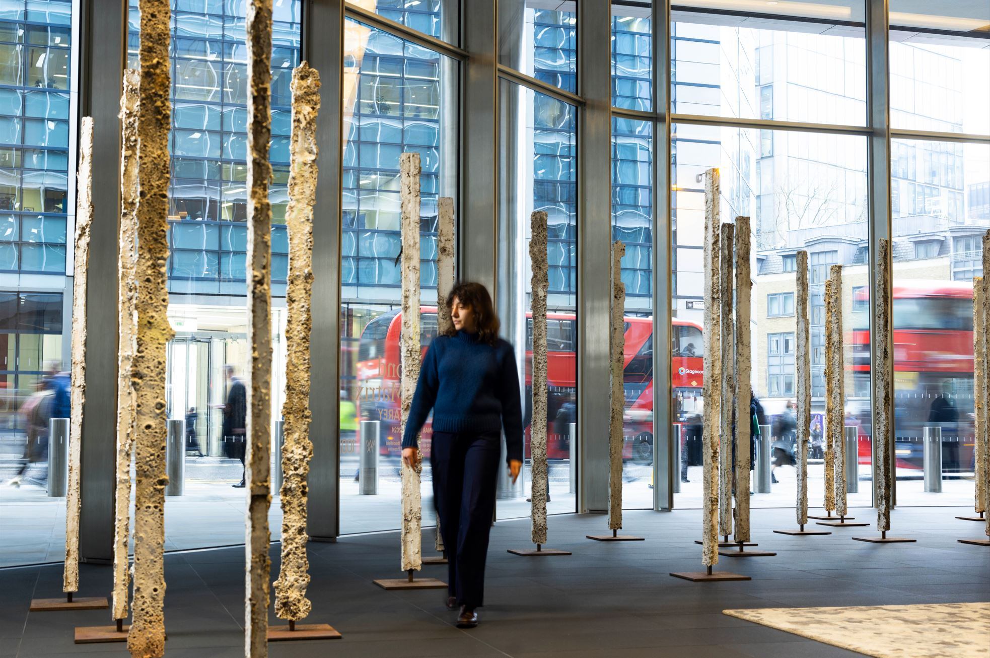 woman walking among sculptures in office building