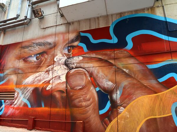 mural of an aboriginal male putting ceremonial face paint on