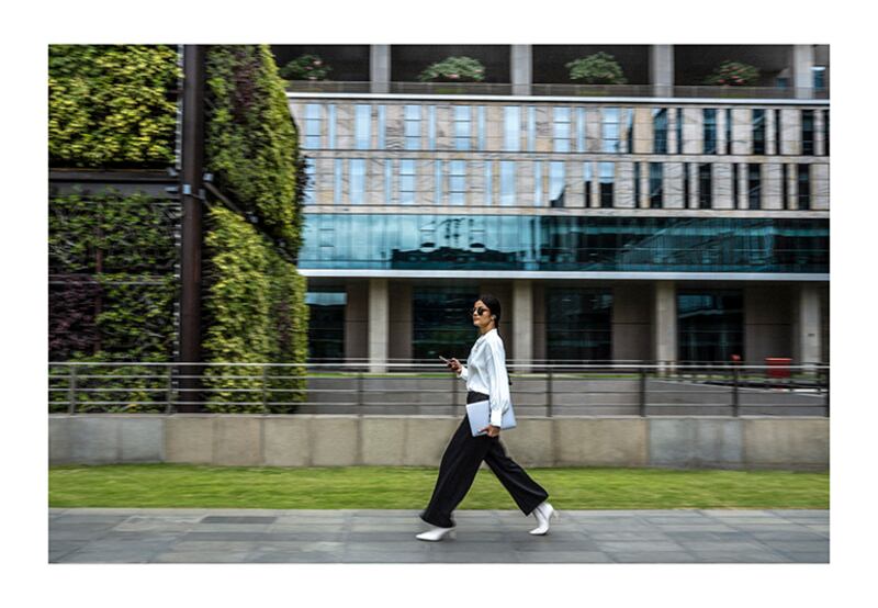 woman in white blouse walking in front of building