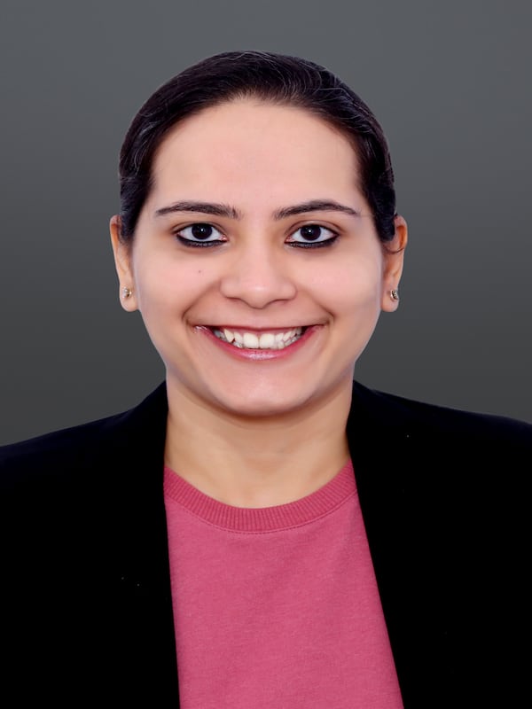 Women headshot with her hair back wearing pink shirt and black blazer.