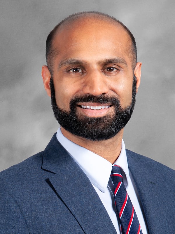 A photo of a man wearing a blue suit with a blue and red striped tie