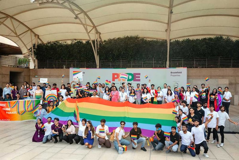 Several individuals standing in front of a pride backdrop for a photo