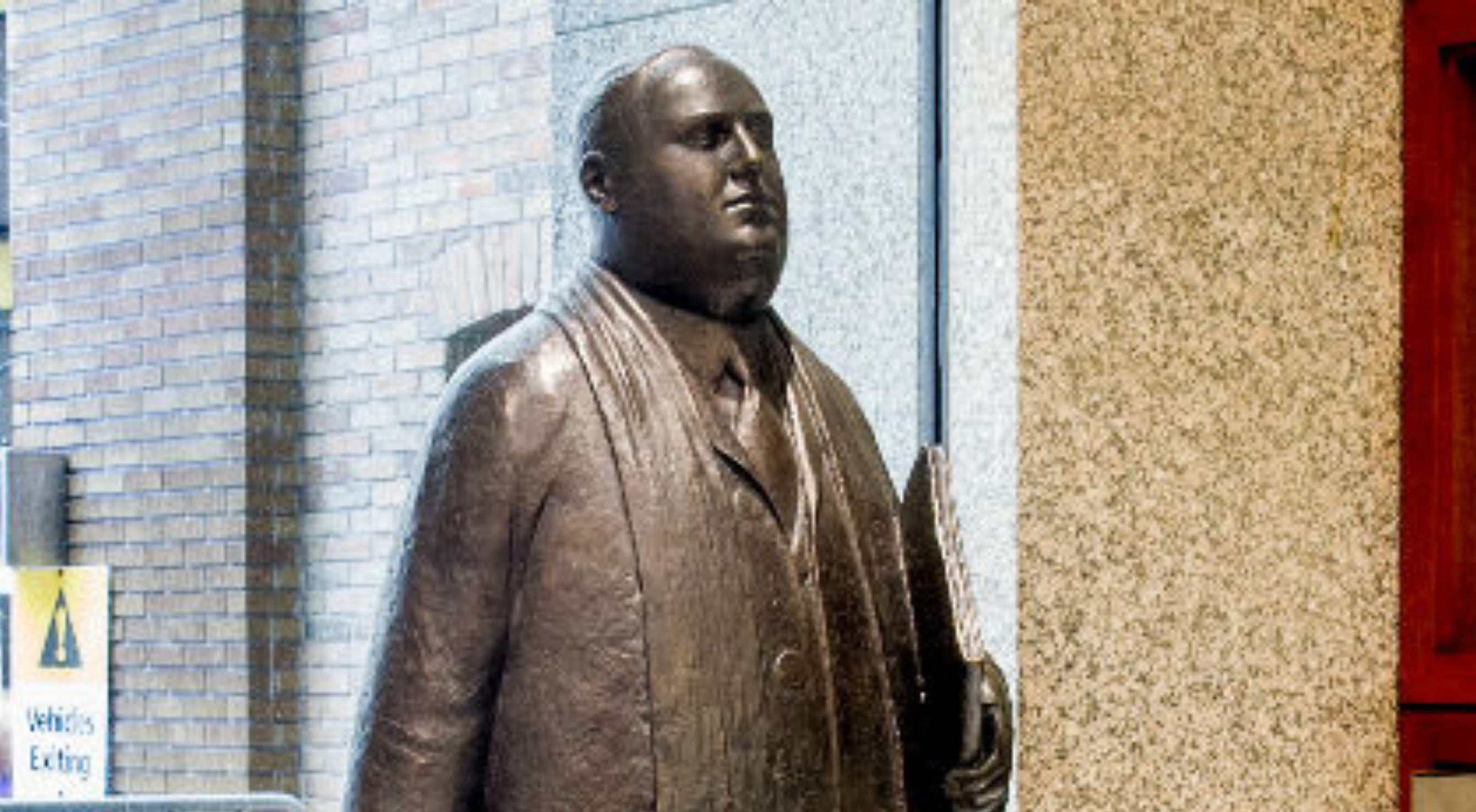 Statue of a bussinessman holding documents.