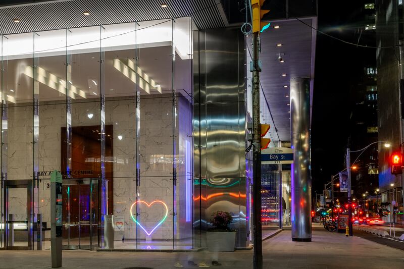 colorful, heart-shaped neon light in office building lobby entrance, view from exterior