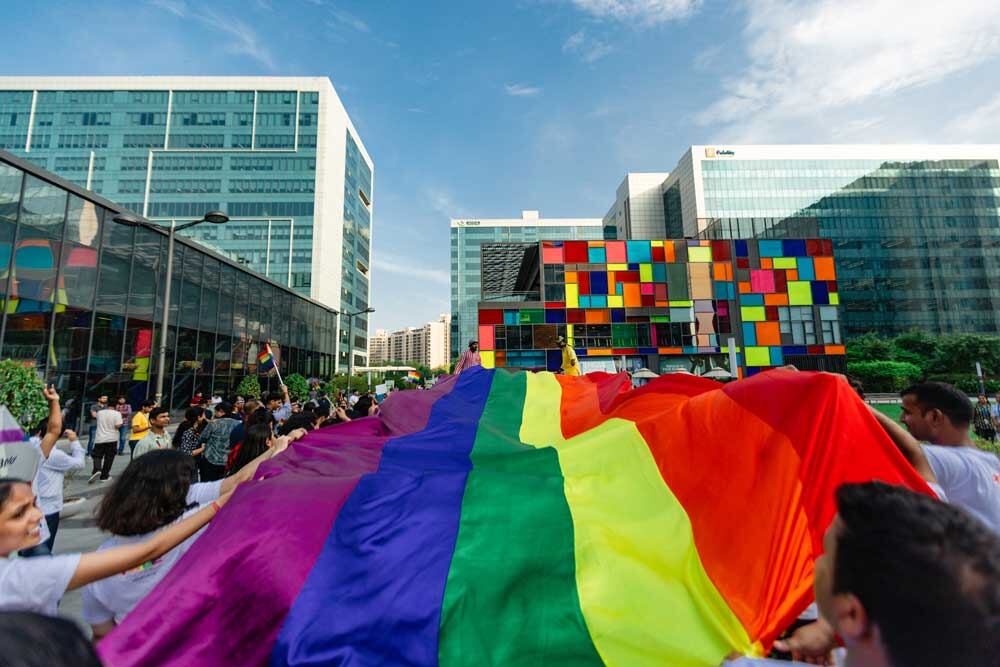 Large pride flag held by individuals during a pride march