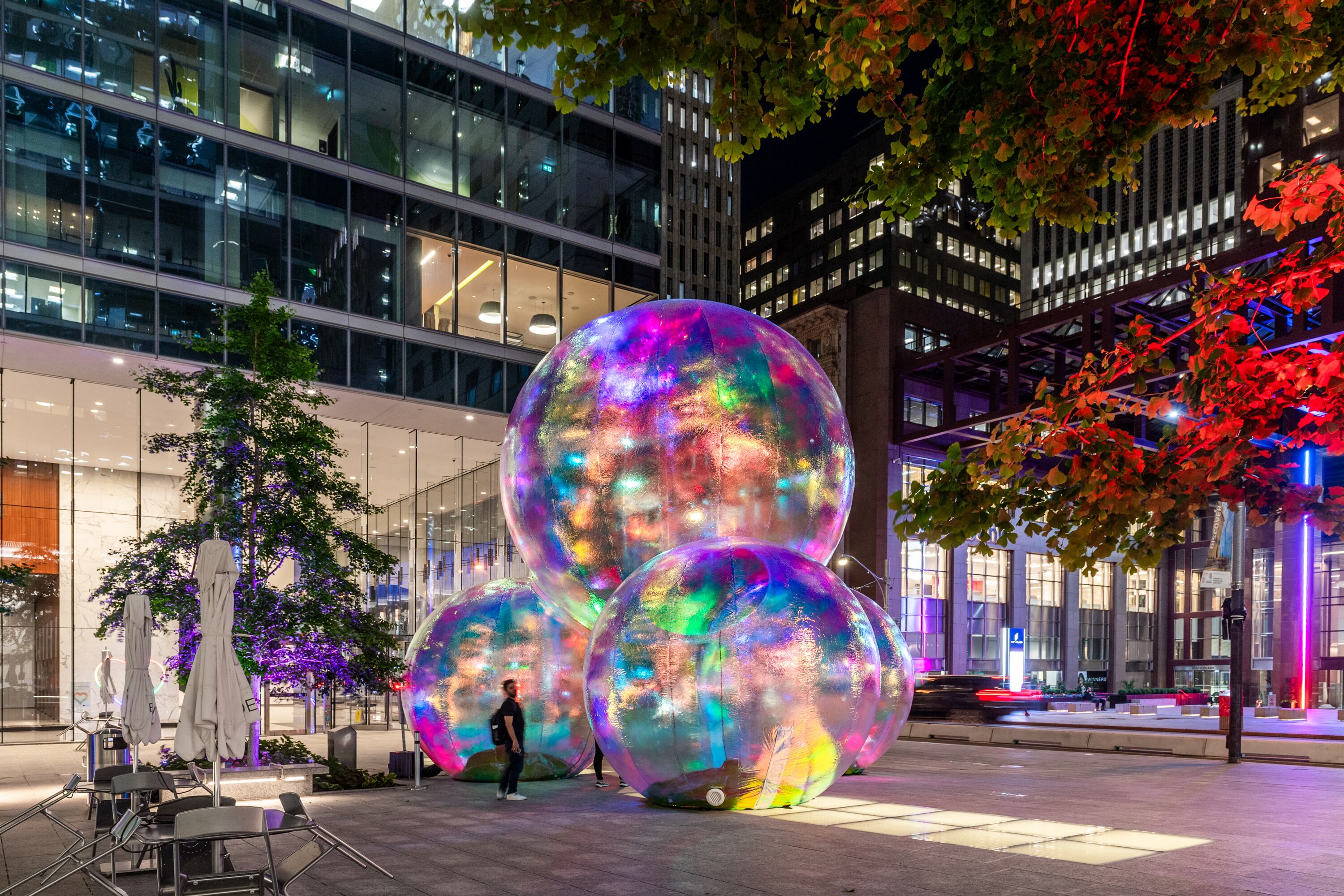 larger-than-life bubble artwork surrounded by office buildings at night