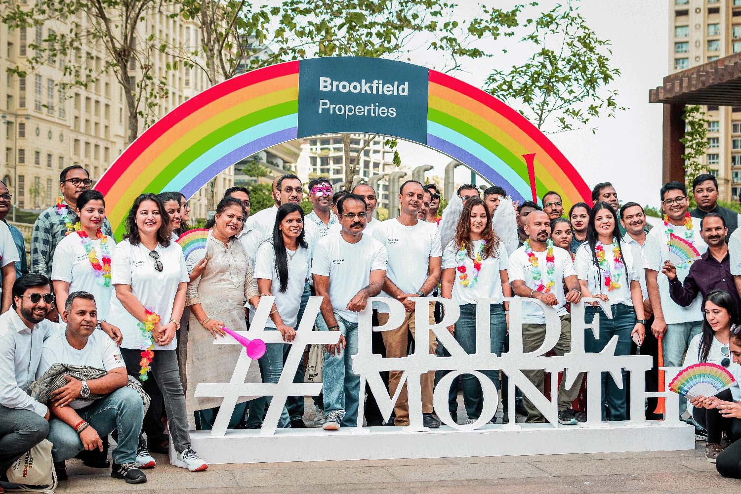 people in white tshirts standing in front of rainbow and Pride Month sign