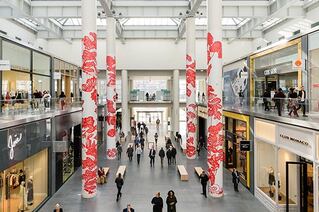 The inside of a white shopping mall. The pillars are decorated with red dragons.