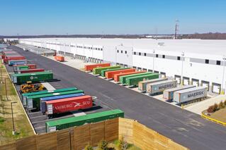 Picture of a warehouse with trucks at the bays