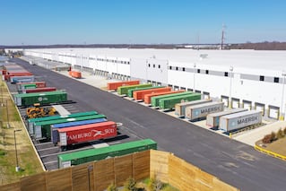 Picture of a warehouse with trucks at the bays