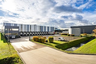 Amsterdam - exterior view of blue and white logistics building with 14 docks and parking area.