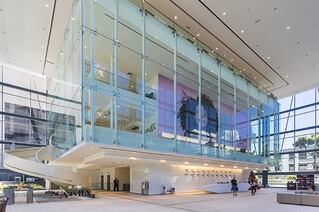 Floor level view of a high end shopping plaza. A glass fronted shop with a large photo of a child takes center stage.