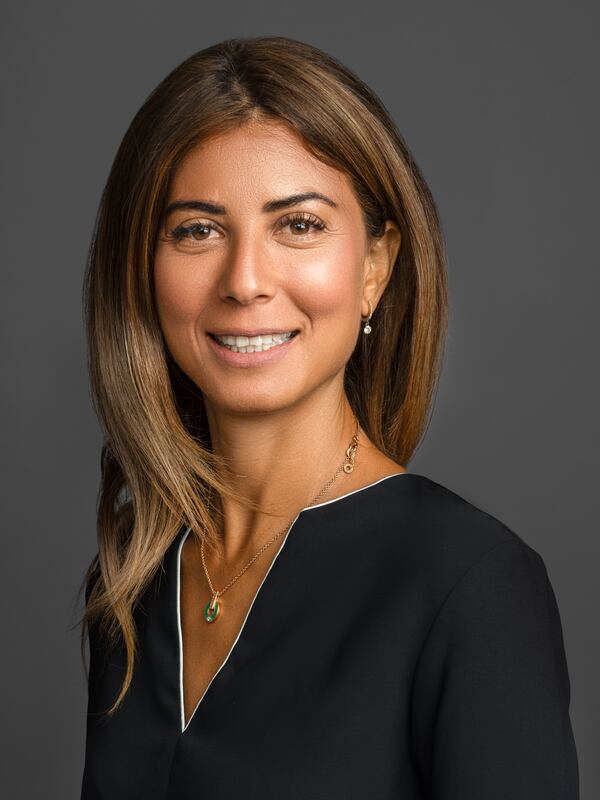 A female headshot, friendly smile, dressed in a v-neck blouse with a