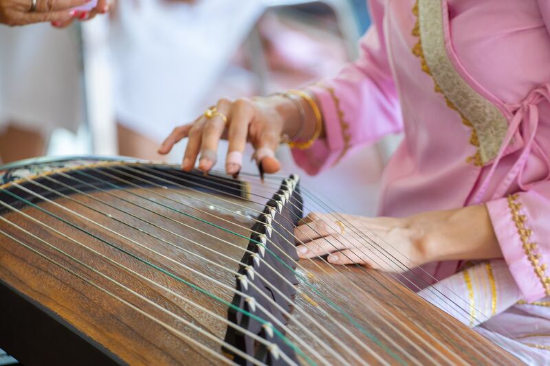 An individual playing a guzheng instrument