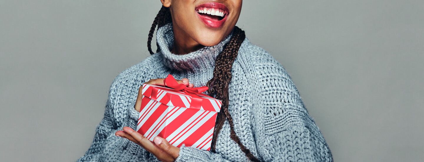 woman in gray sweater holding holiday gift