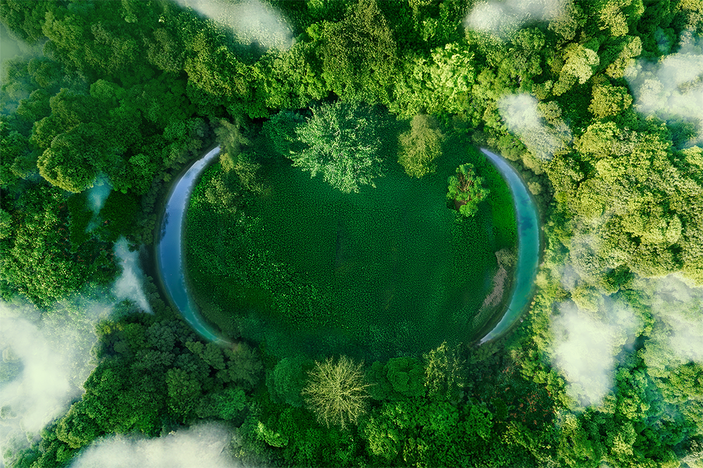 aerial view of crescent shaped water pools surrounded by forest and clouds