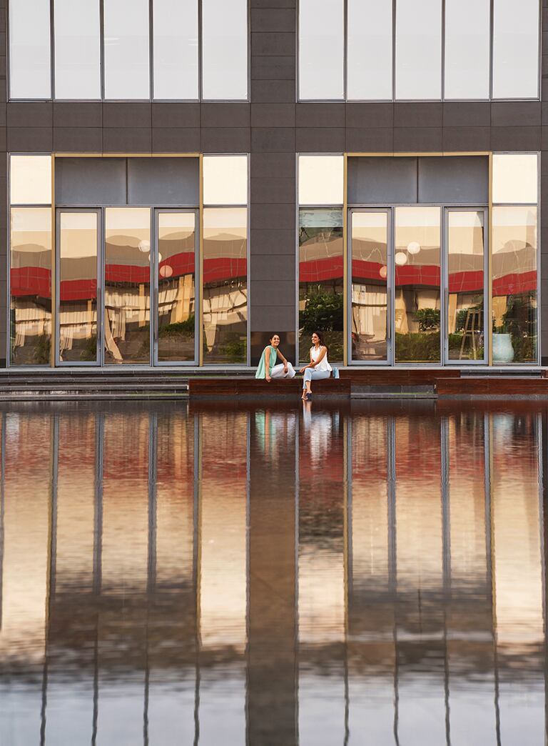 2 women sitting in front of pond outside offices