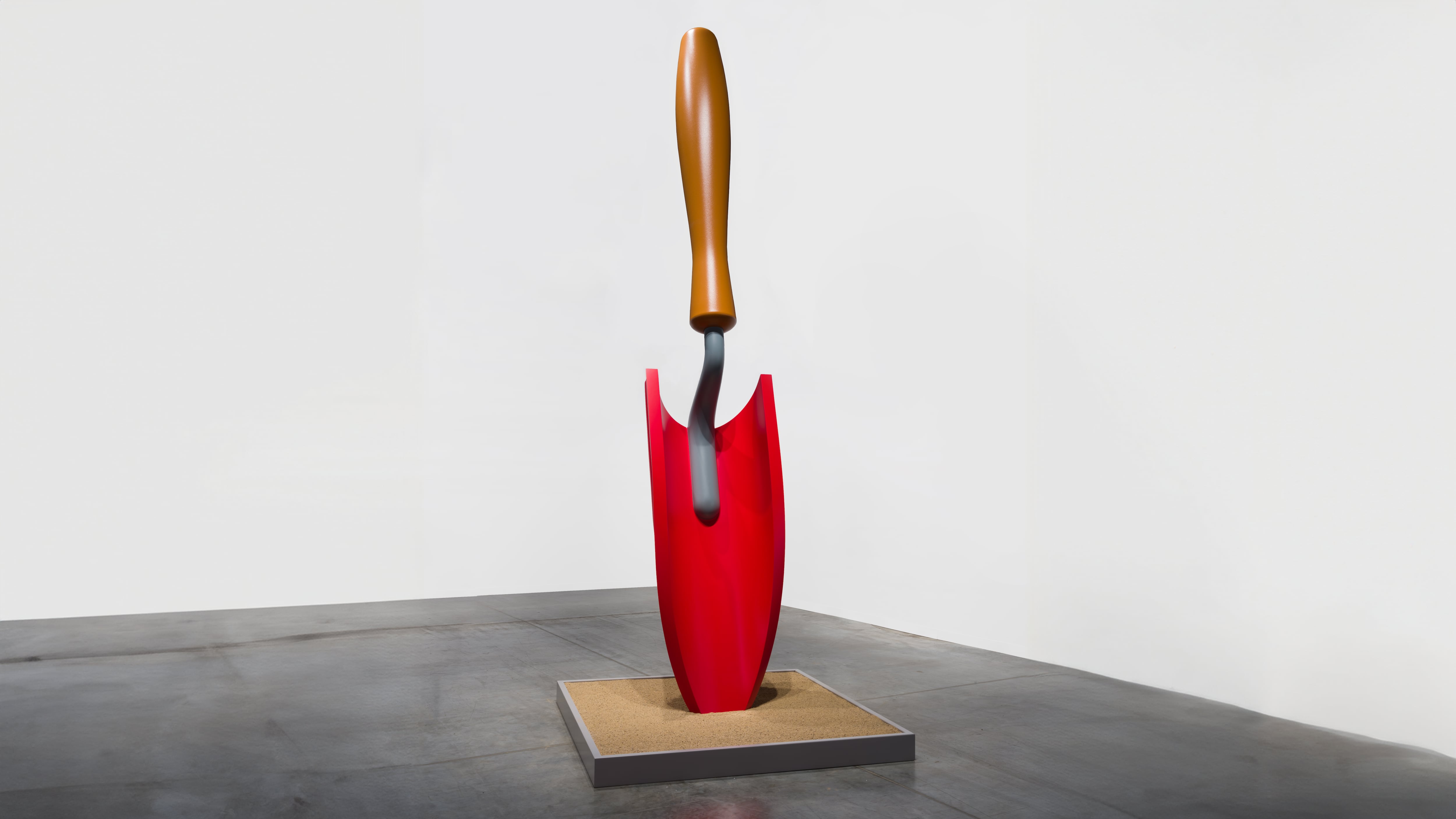 A sculpture of a red shovel propped vertically