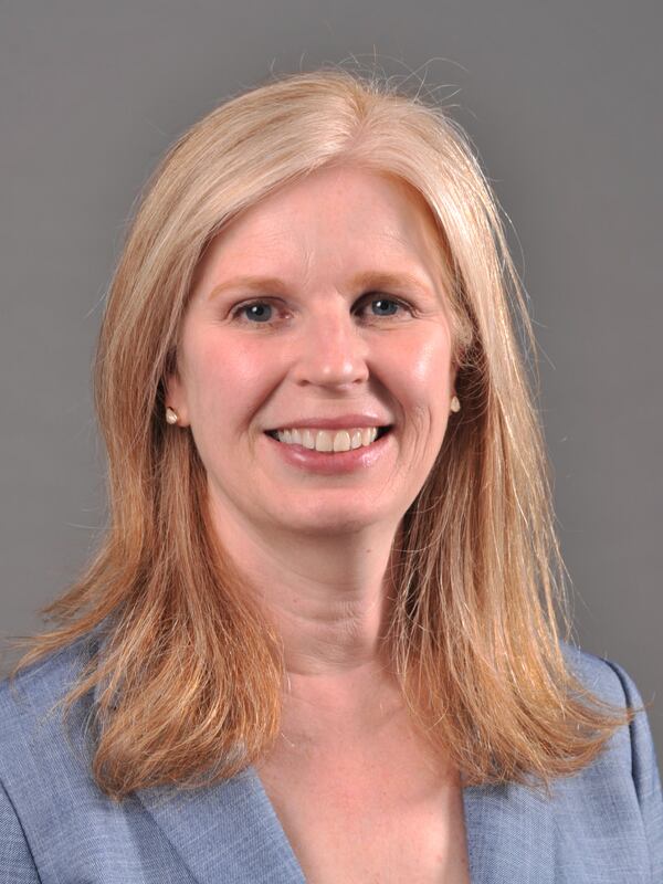 Headshot of a woman with a light blue blazer, blond mid-length hair
