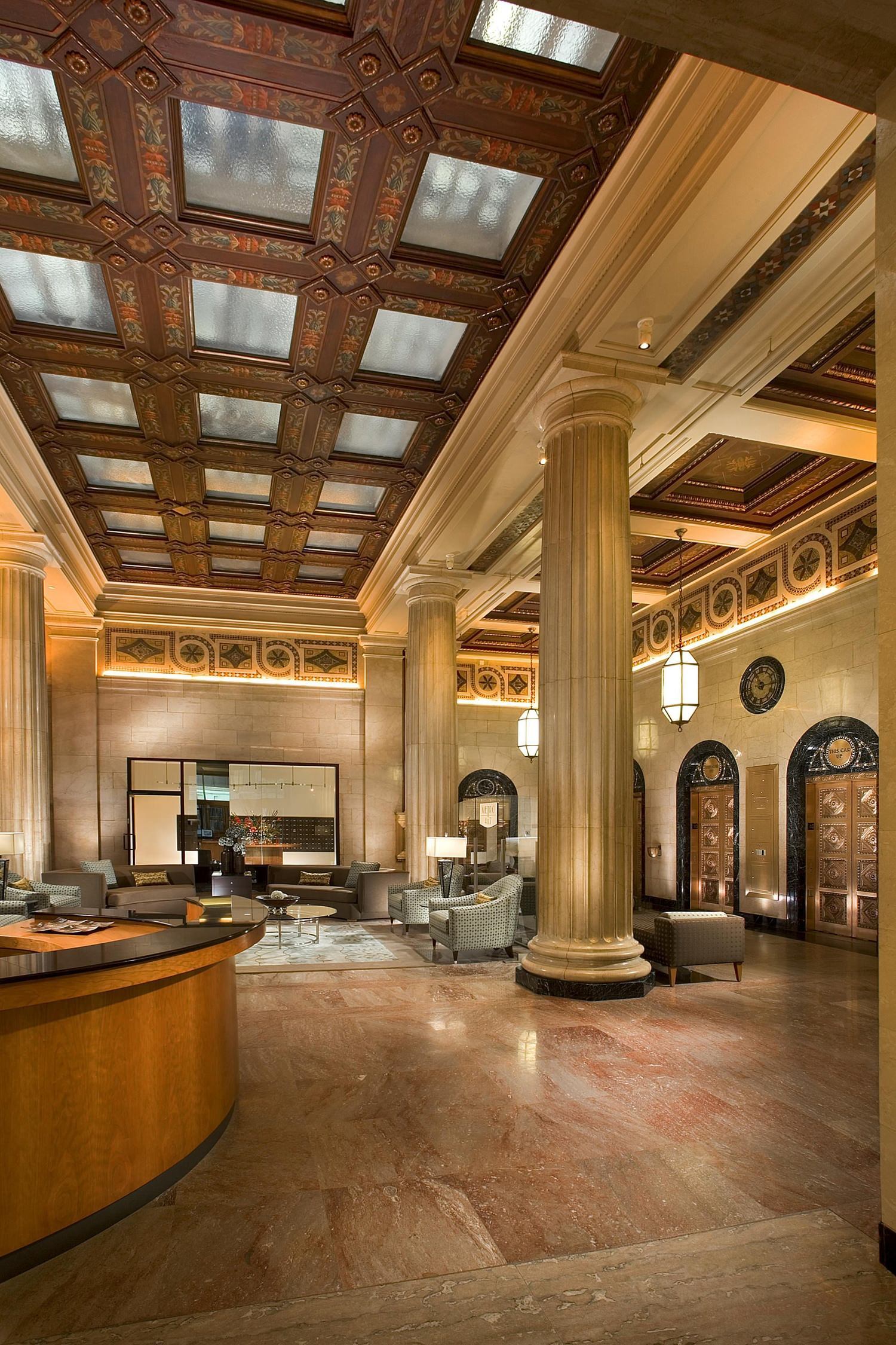 The inside of a lobby of a hotel that has some large columns in the middle of it.