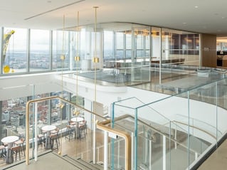 Inside of office building with glass walls, conference room, stairs and high top seating