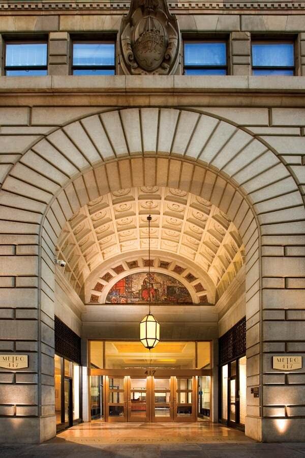 A building that is made out of brick and has a large arched entryway to get in to the doors of it.
