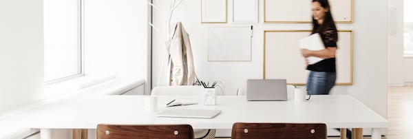 blurred woman walking in front of white table in office